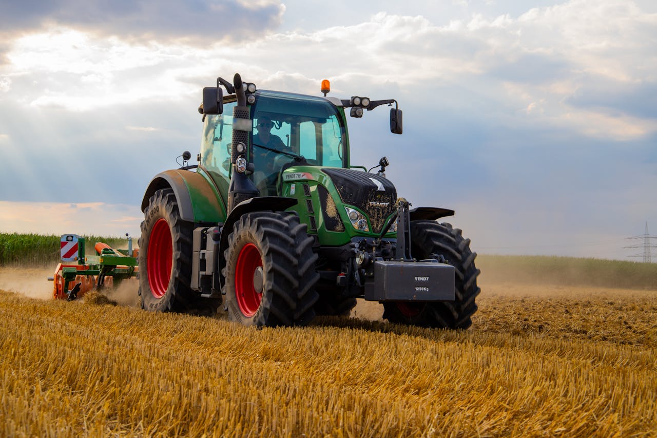 Mastering the First Impression: Your intriguing post title goes here A powerful green tractor plowing a dusty wheat field under a cloudy summer sky in rural Germany.